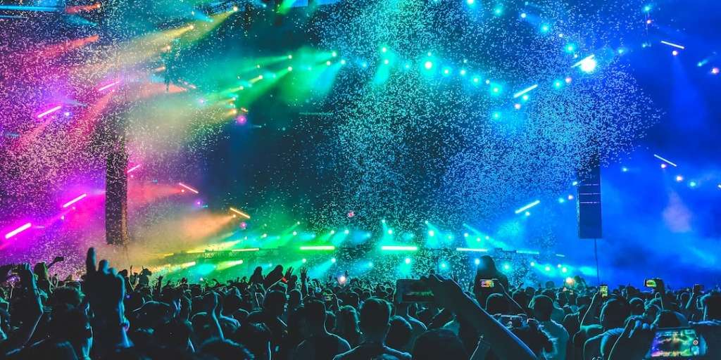 Taylor Swift Top 5 Songs: Excited crowd at a live music concert, with colorful stage lights and the artist performing on stage.