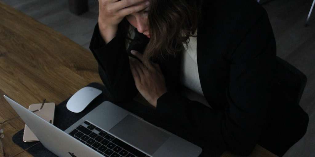 Professional woman seeking to escape the 9-to-5, feeling overwhelmed with traditional work model at her laptop.