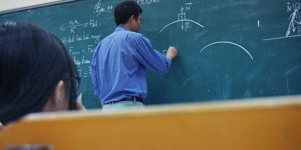 Teacher illustrating Grade 12 math exam secrets on a chalkboard during a lesson.