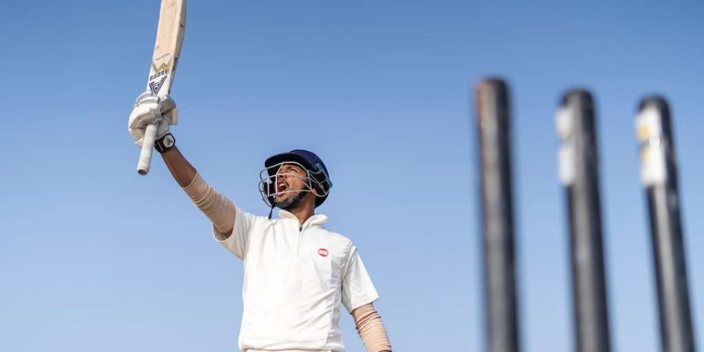 Cricketer raising his bat in triumph during the Pakistan vs South Africa 2023 World Cup match with stumps in the background.