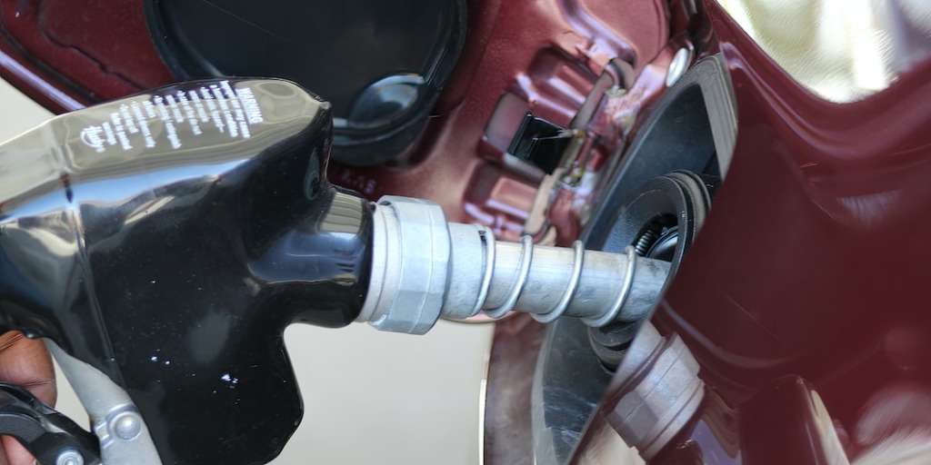 Refuelling a vehicle with a petrol nozzle, highlighting the intricacies of petrol price fluctuations.