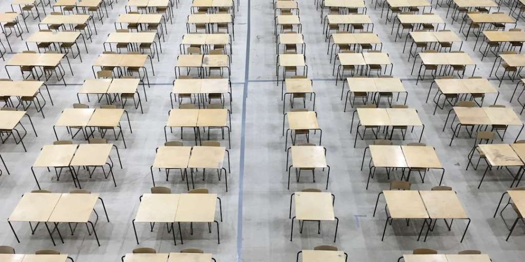 Rows of desks in an examination hall ready for students to take Matric Afrikaans Paper 1.