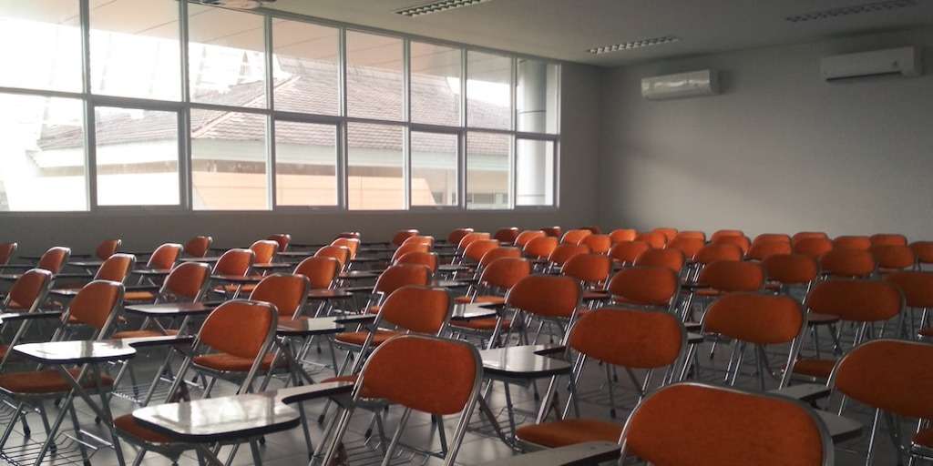 Empty classroom with rows of orange chairs, ready for Matric Mathematics Exams as outlined in the Matric Mathematics Exams Guide.