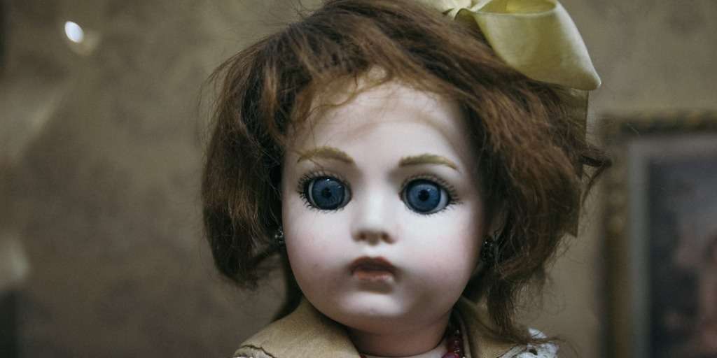 A haunted doll sold for £10,000, with penetrating blue eyes and a vintage bow, embodies a mysterious past.