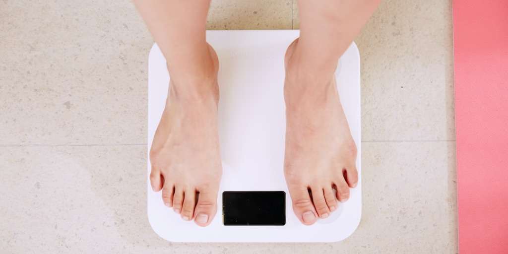 A person standing on a scale, indicative of weight measurement, showcasing the concept of 'Fat-Burning Sleep Vegetable' for weight loss.