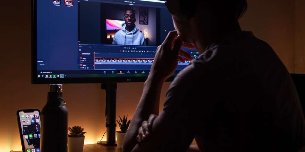 A content creator works on editing a video featuring a person on a computer screen, aiming for 'Viral YouTube Success'.