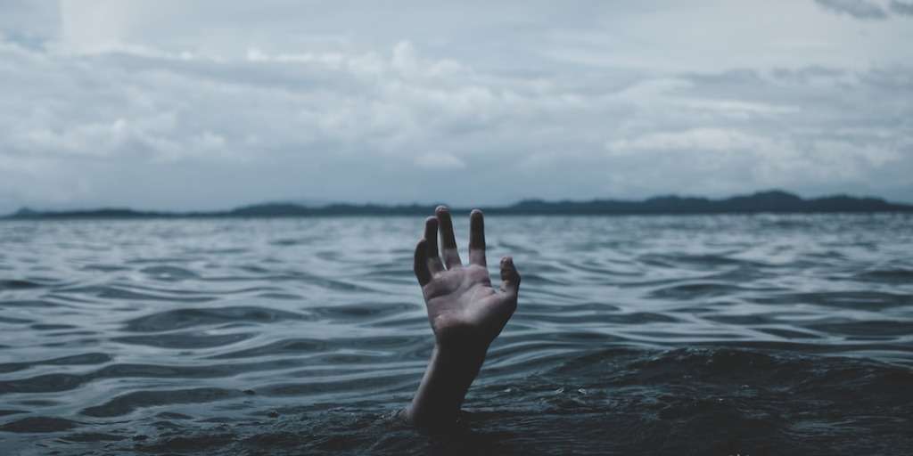 A hand reaching out of the water, symbolizing a cry for help or 'Karma Delivers Justice' in a serene sea setting.