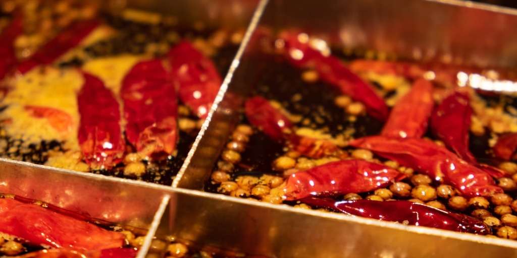 Assorted spices, including bright red chilies and peppercorns, are displayed in sections, showcasing the variety needed to build spice tolerance.