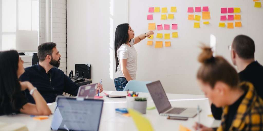 A project team attentively listens to a leader discussing strategy, epitomizing effective DIY Project Management.