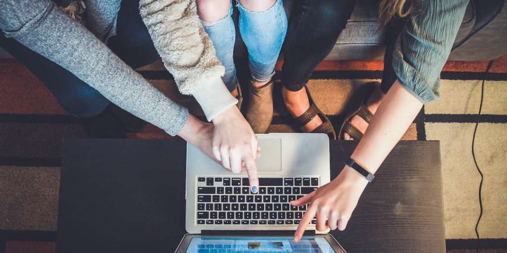 Three people collaborating on a laptop, using online resources to Master New Languages Fast.