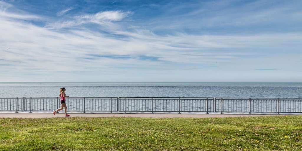 A woman jogs by the sea, embodying 'The One Thing Successful People Do Every Morning.'