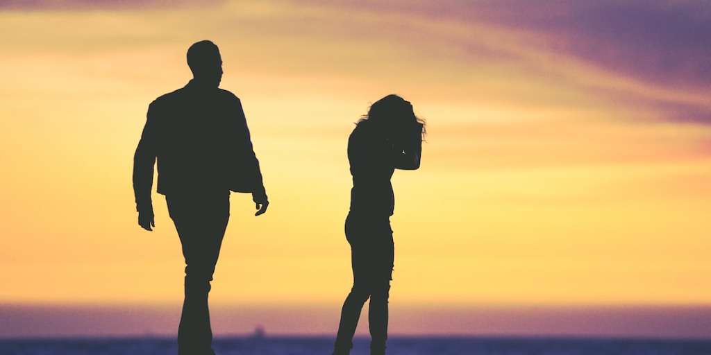 Silhouetted couple apart at sunset, depicting 'Social Media's Impact on Relationships' in disconnect.