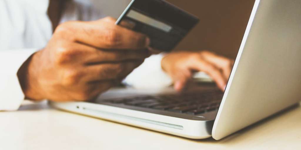 Man using credit card and laptop to implement strategies to Double Your Income Overnight online.