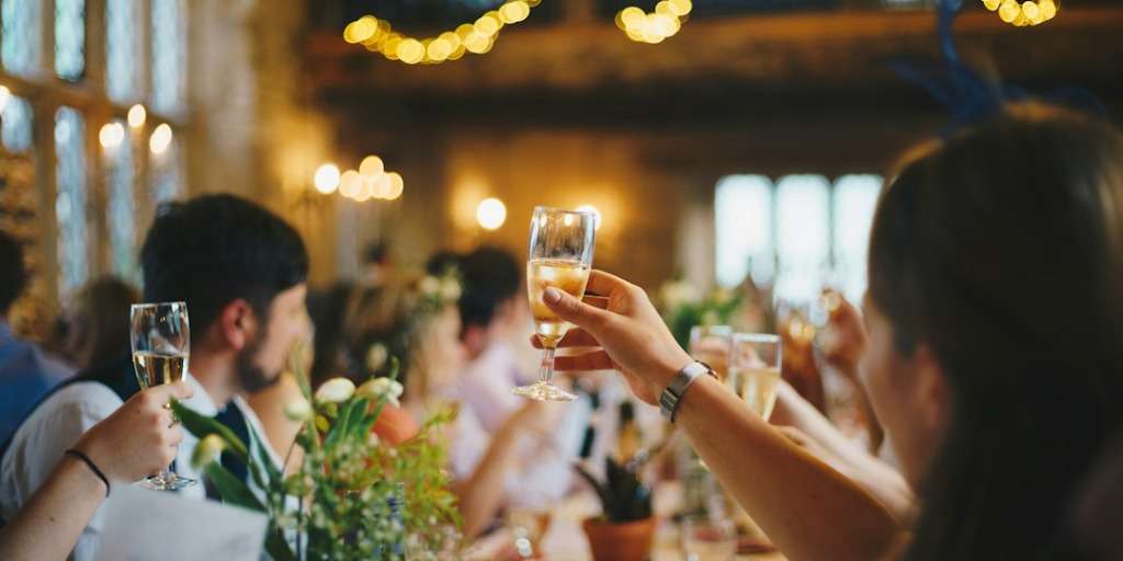 Party Planning: Guests celebrating with raised glasses at a vibrant party - a key aspect of successful party planning.