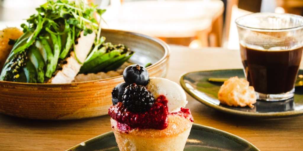 Healthy muffin recipe topped with fresh berries, served with coffee and a side of greens.