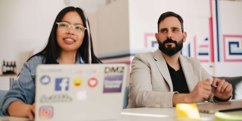 Two co-workers engaged in discussion at a modern office desk, symbolizing the dynamics of dating a co-worker.
