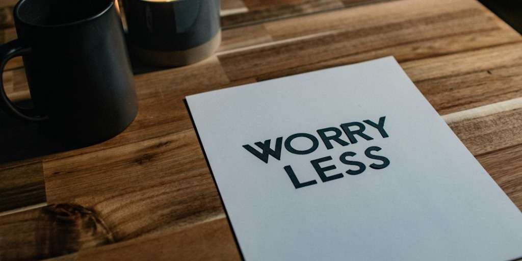 Paper with 'WORRY LESS' printed, concept for 'How to Make Sure Your Anxiety Doesn't Get Too Far' guide.