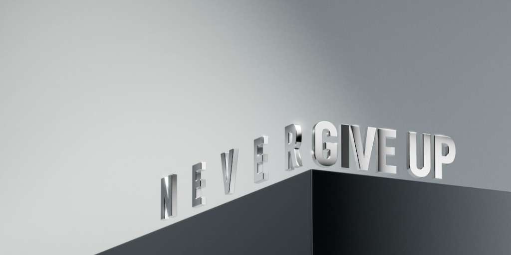 3D metallic letters on a corner spelling 'NEVER GIVE UP' in a minimalist style.