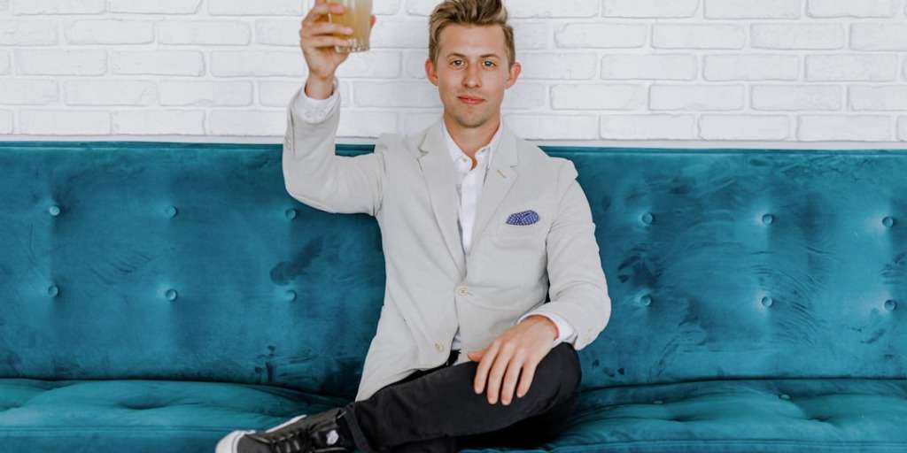 Man toasting success on teal sofa, embodying Millionaires Investment Strategy with style and confidence.