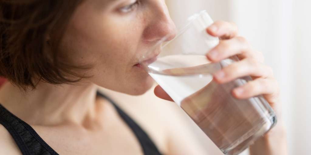 Woman drinking water, using simple hydration trick to lose weight fast and improve health.