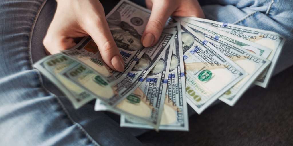 Person counting a stack of hundred-dollar bills, representing the Money Mistake 90% of People Make.