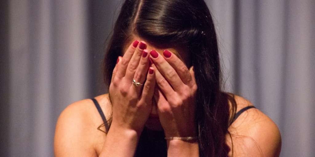 A distressed woman covers her face with her hands, embodying the struggle of how to deal with trauma.