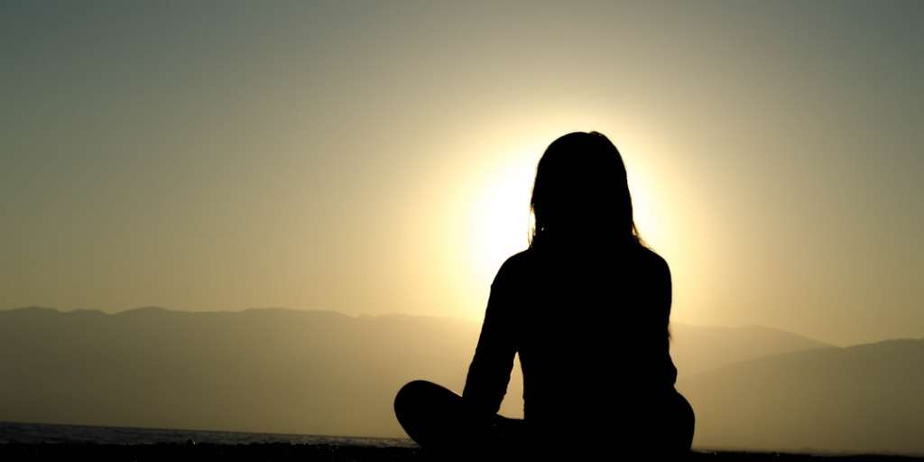 A silhouette of a person meditating against a sunset, embodying "Staying Calm in Crisis" with serene poise.