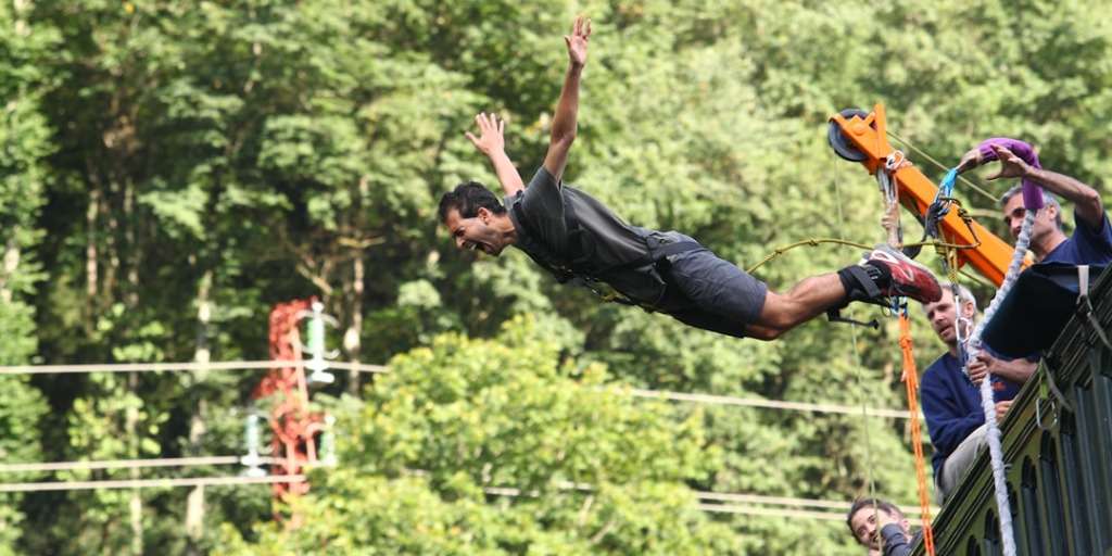 Man leaping from platform in forest, embodying what you need to know before bungee jumping.