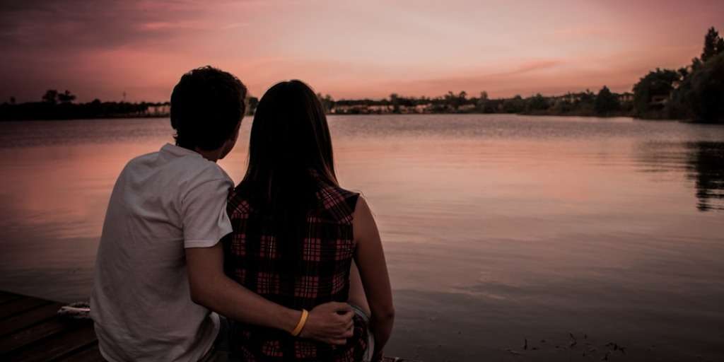 Couple sitting together on a dock at sunset, overlooking a tranquil lake. Soulmate Test Revealed.