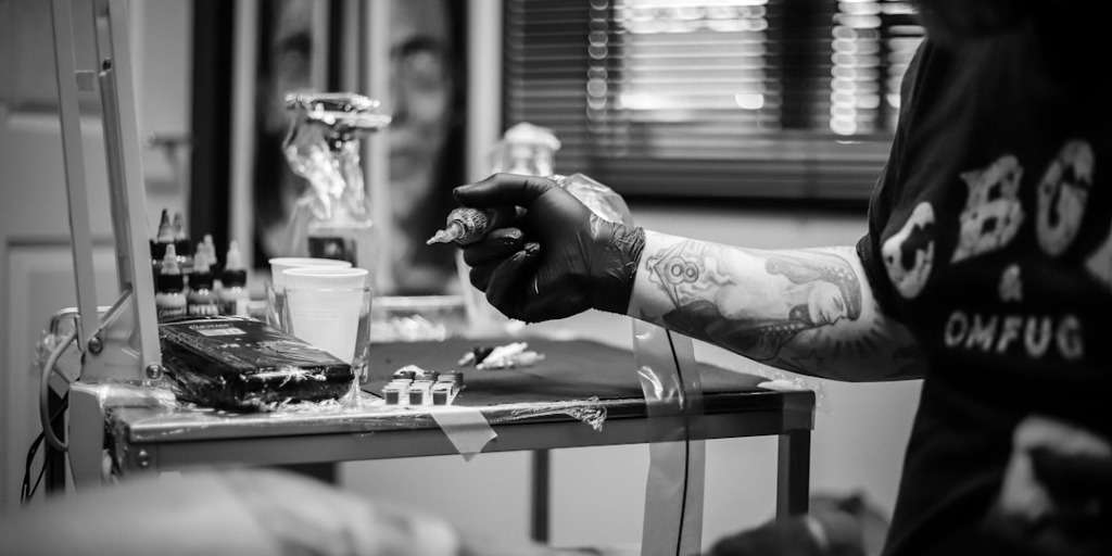 Tattoo artist preparing for a session on Most Painful Tattoos to Get, focusing on equipment.