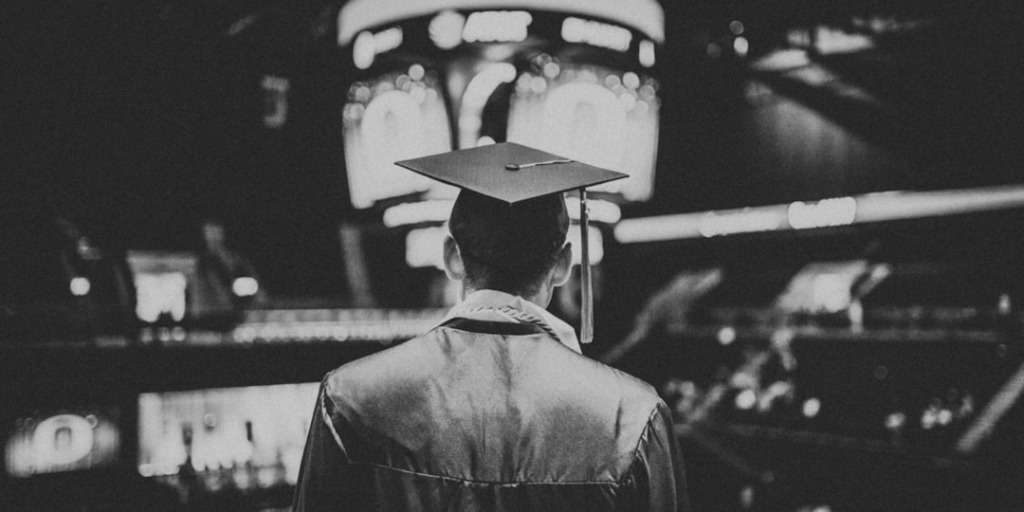 Graduate in graduation attire facing an auditorium